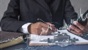 Profissional de terno analisando gráficos financeiros impressos