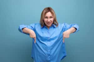 Mulher de camisa azul apontando para baixo sobre fundo azul