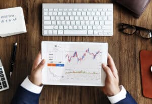 Mãos segurando tablet com gráfico de mercado financeiro