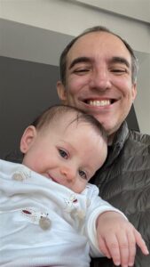 Homem sorrindo segurando um bebê no colo