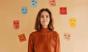 Mulher em frente a papéis com expressões faciais desenhadas